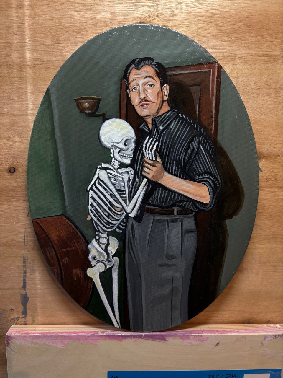 Heather Lenters' oval painting of a man holding a skeleton